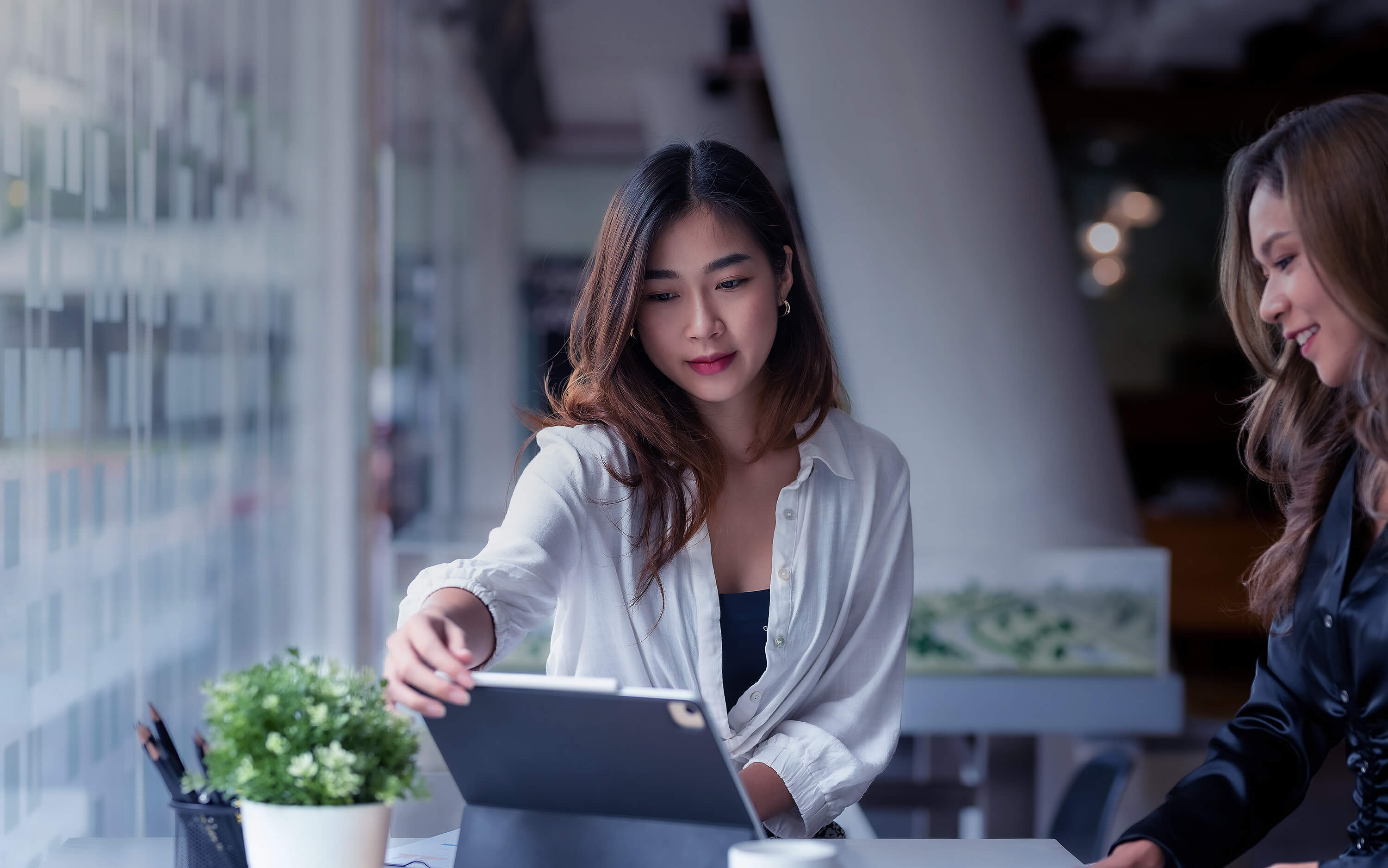 two women consult over a laptop