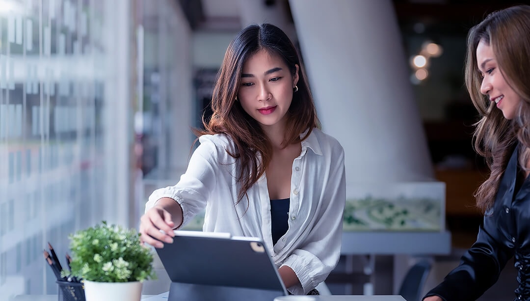 two women consult over a laptop