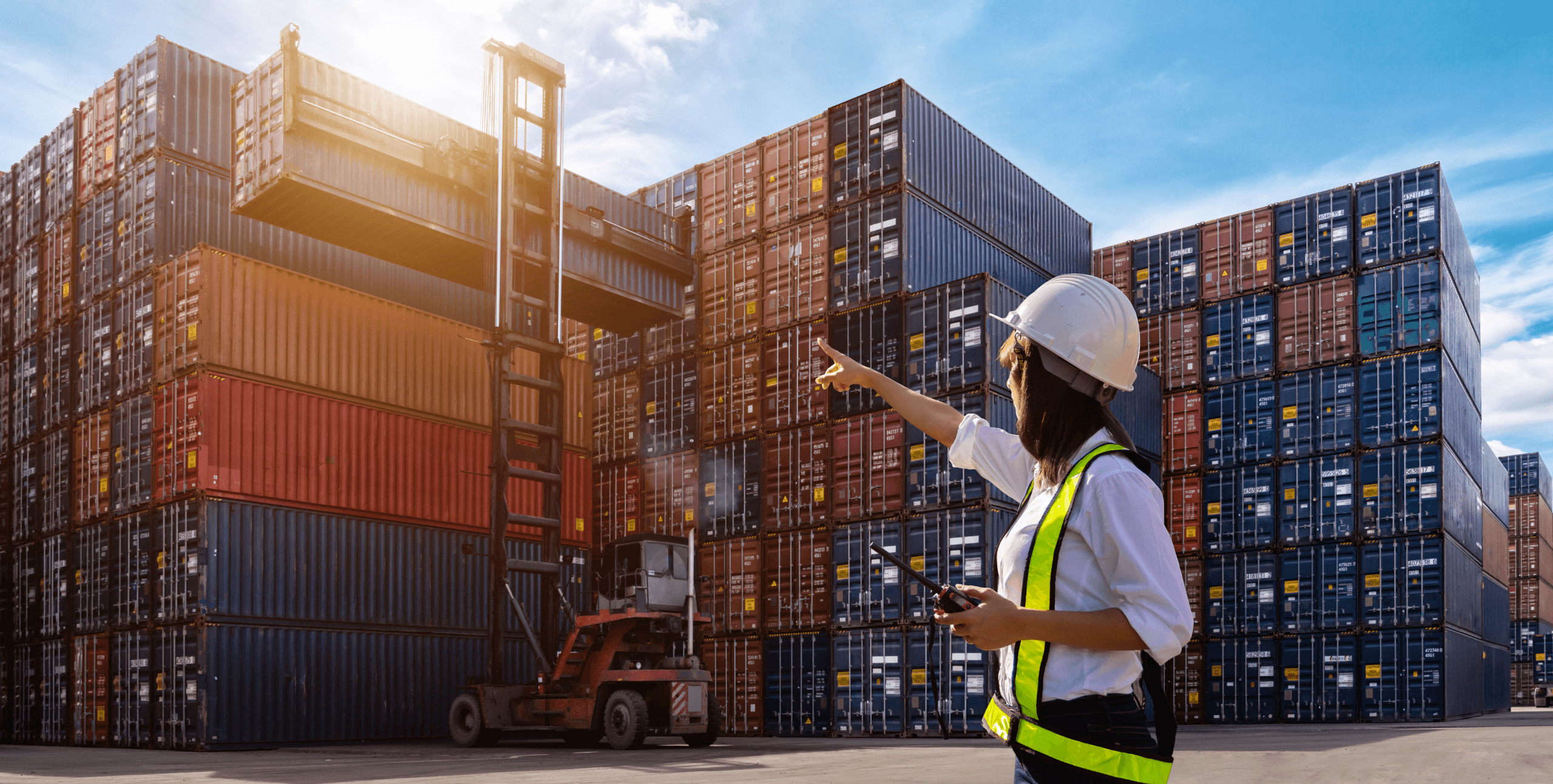 Women directed forklift moving shipping containers at a dock