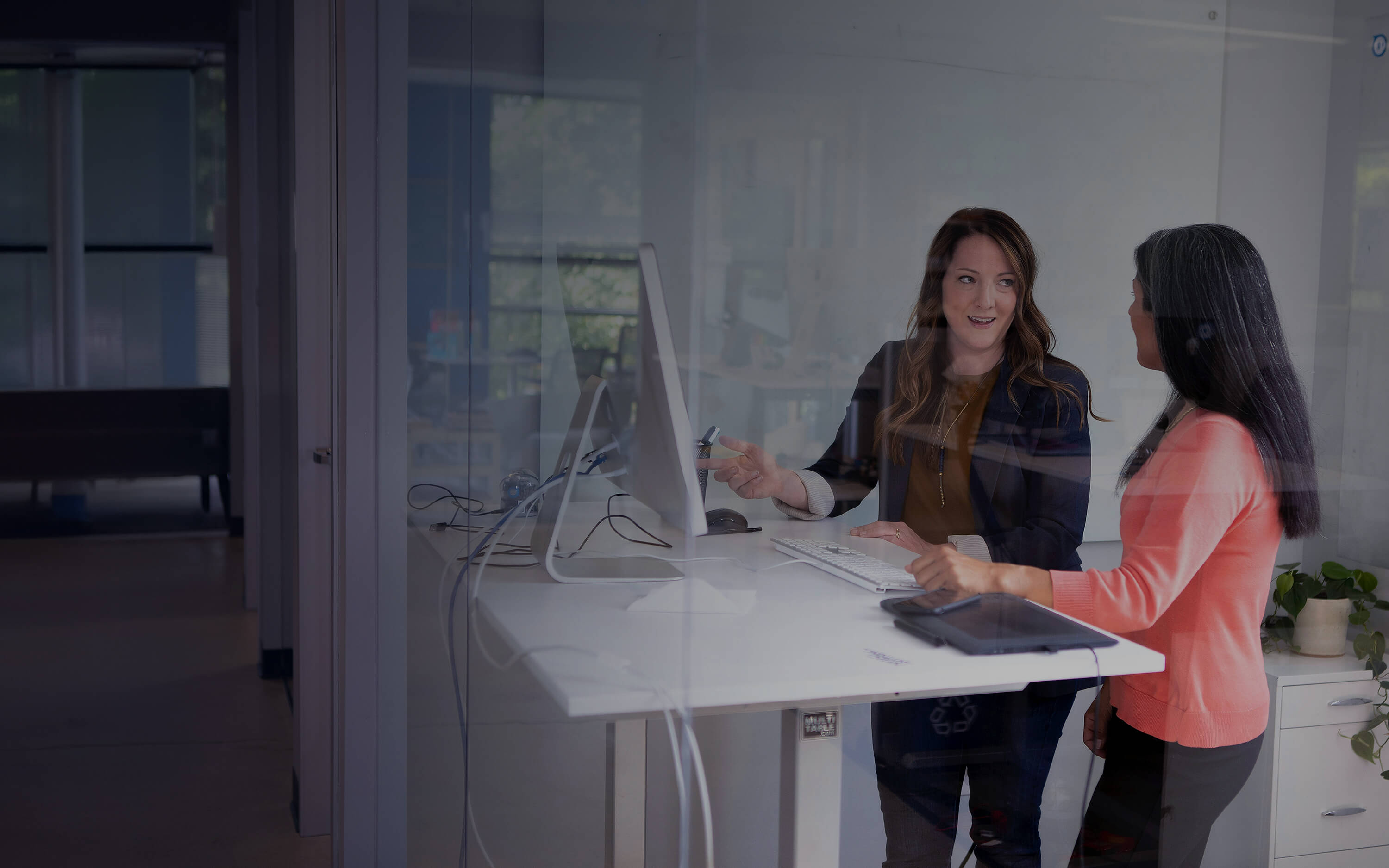 Two women talking about content on a screen