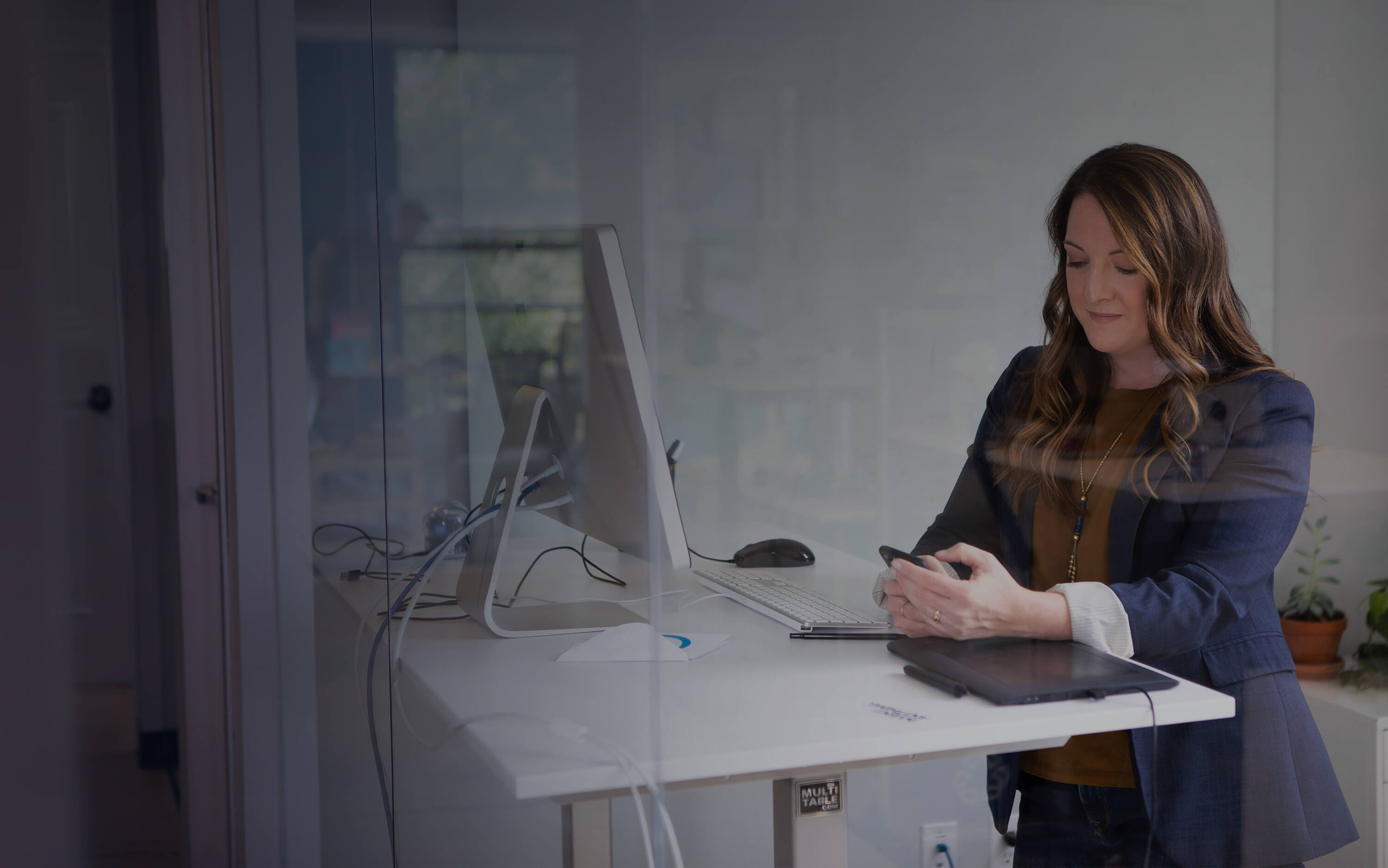 Woman checks her phone at her work desk