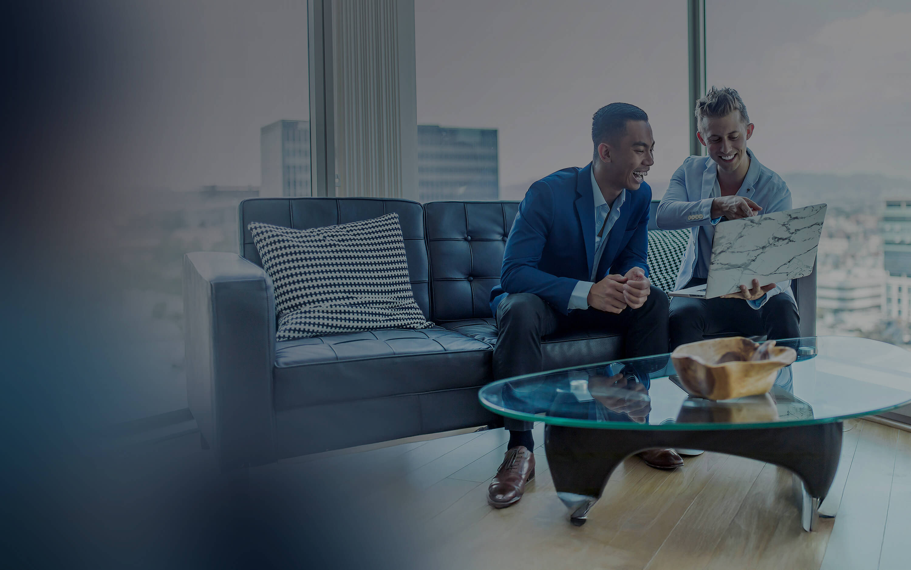 Two people sitting on a couch looking at a laptop